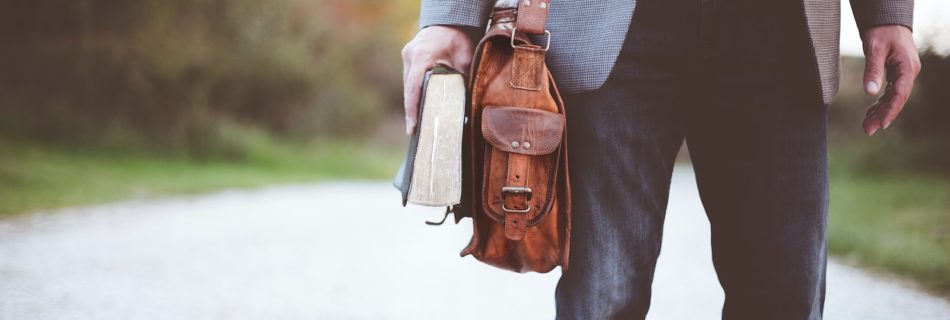 man holding book on road during daytime